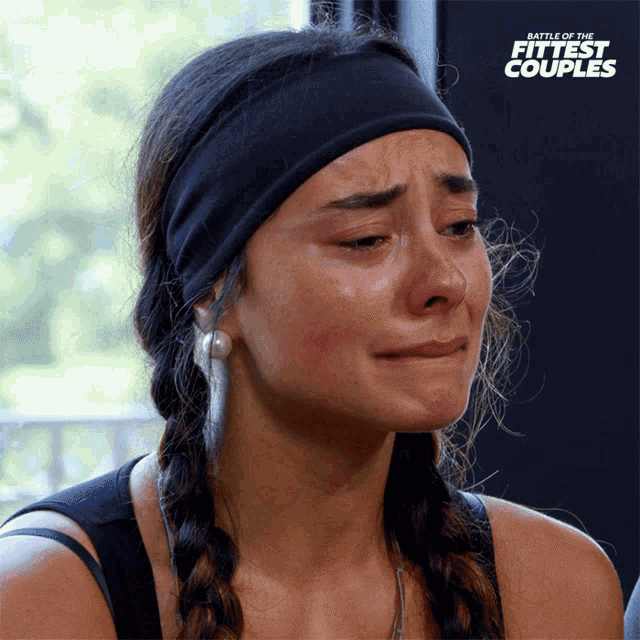 a woman is crying in front of a battle of the fittest couples sign