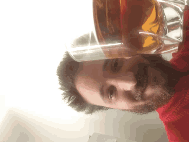 a man with a beard is smiling while holding a glass of beer