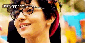 a close up of a woman wearing glasses and a headband smiling .