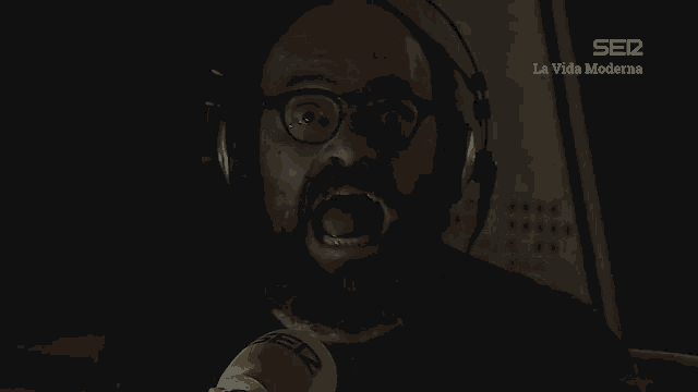 a man wearing headphones and a yellow microphone with the words ser la vida moderna above him