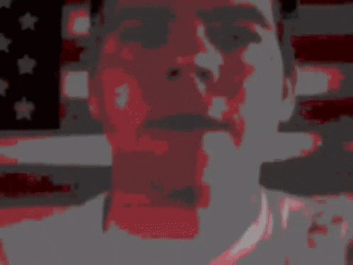 a close up of a man 's face with an american flag behind him