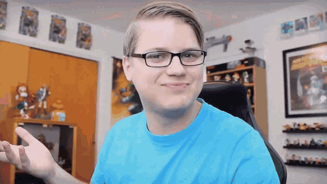 a young man wearing glasses and a blue shirt is sitting in a chair
