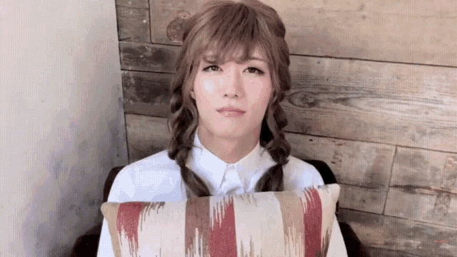 a woman with braids is sitting in a chair with a pillow in front of her