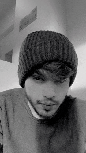 a black and white photo of a man wearing a beanie and sweater