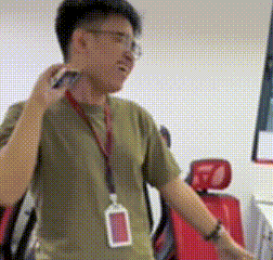 a man wearing glasses and a lanyard with a name tag around his neck is talking on a cell phone .