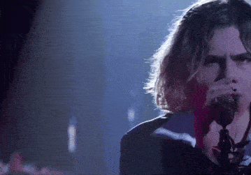 a young man singing into a microphone with a rose in his hand