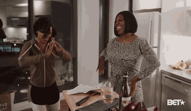 two women laughing in a kitchen with a bet logo on the bottom right