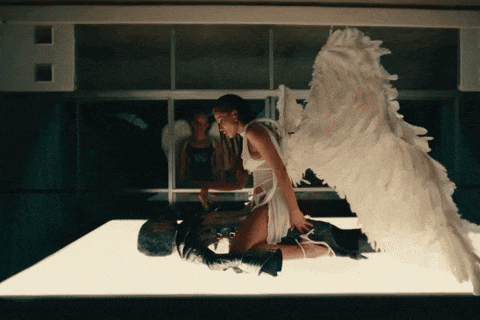 a woman with angel wings is kneeling down on a table