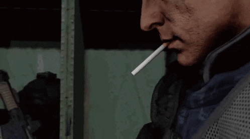 a man wearing black gloves is smoking a cigarette with smoke coming out of his mouth