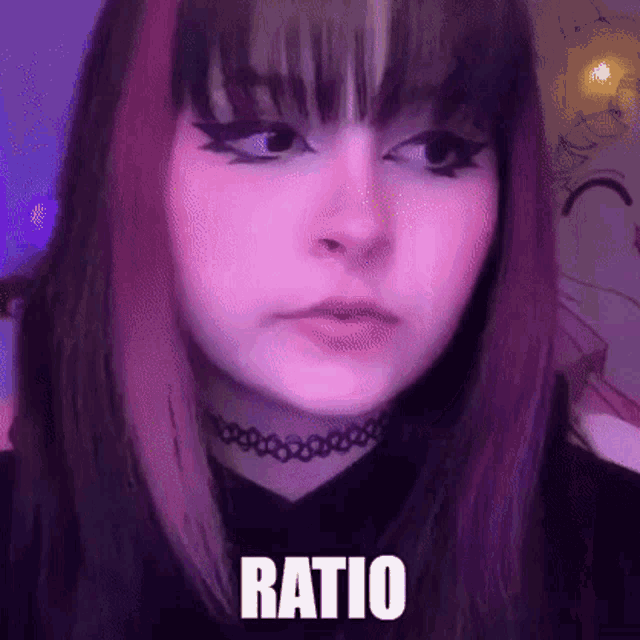 a girl with purple hair and a choker on her neck is making a funny face .