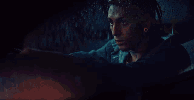a man with a tattoo on his face is sitting in the back seat of a car