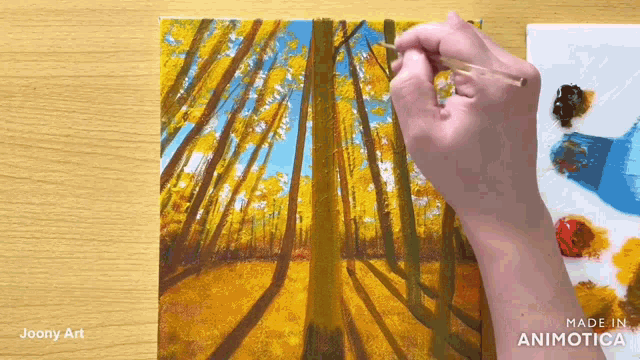 a person is painting a picture of a forest with a brush .