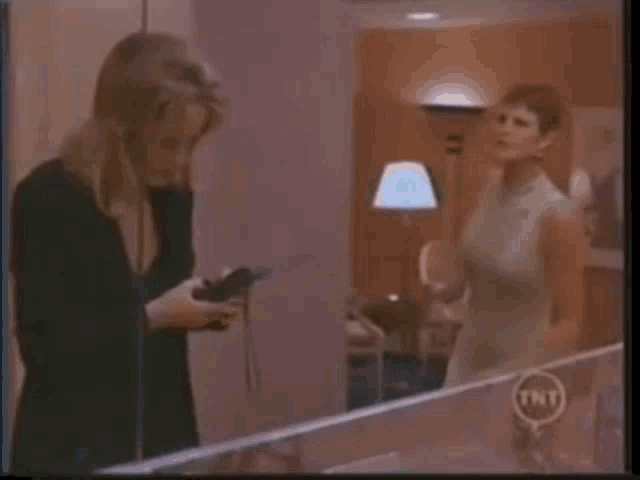two women are having a fight in a kitchen and one of them is holding the other 's arm .
