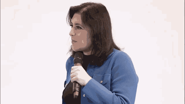 a woman wearing a blue jacket is holding a microphone