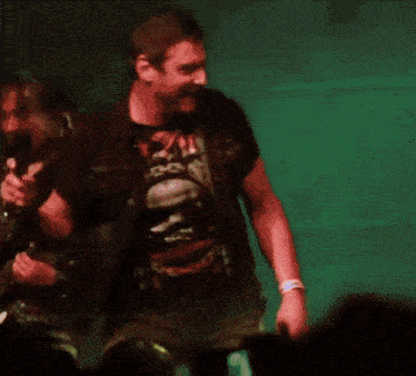 a man wearing a t-shirt that says ' rock ' on it stands on stage
