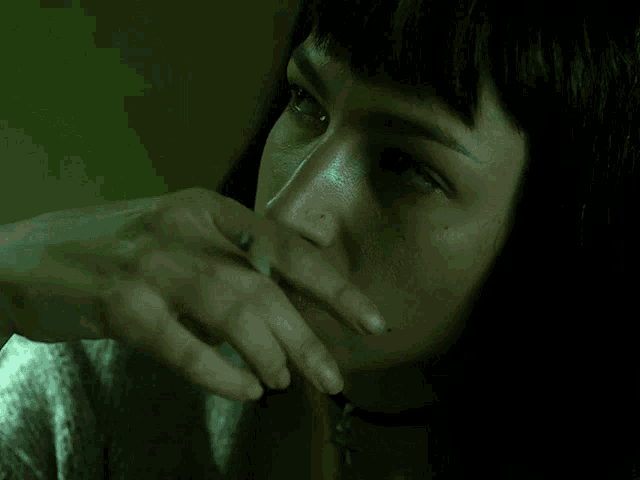 a close up of a woman 's face with her hand on her face
