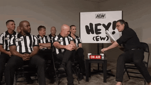a group of referees are sitting in front of a sign that says hey ( ew )