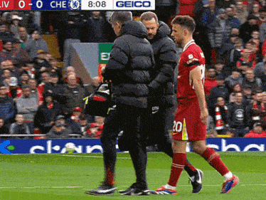 a soccer player with the number 20 on the back of his jersey is being helped off the field
