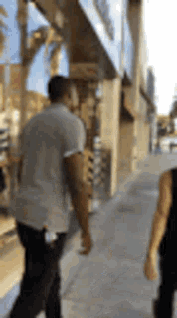 a man and a woman are walking down a sidewalk next to a building .
