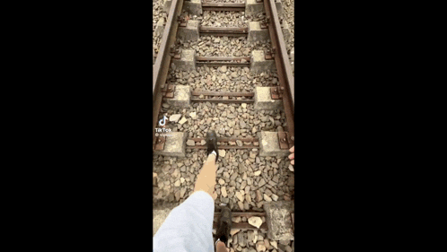 a person is standing on train tracks with their feet on the tracks