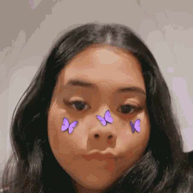 a girl with purple butterflies on her face looks at the camera .
