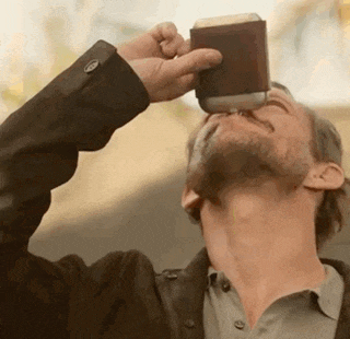 a man with a beard is drinking a beer from a can .