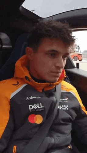 a man wearing a dell jacket sits in a car seat