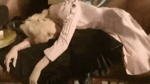 a woman in a pink dress is laying on a couch with her legs crossed .