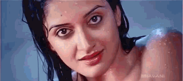 a close up of a woman 's face with water drops on her hair .