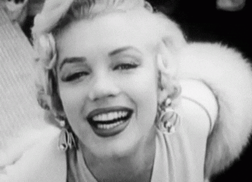 a black and white photo of marilyn monroe smiling with a fur collar .