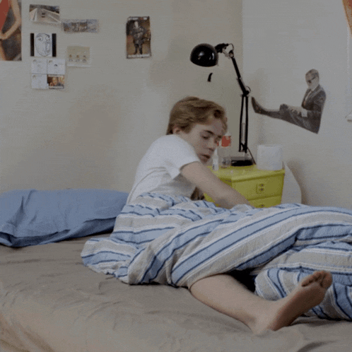 a man in a white shirt is laying on a bed with a bottle of coke in the background