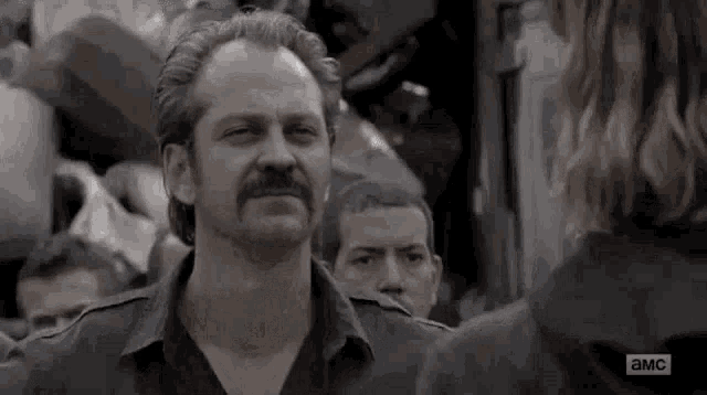 a man with a mustache is standing next to a woman in a crowd of people .