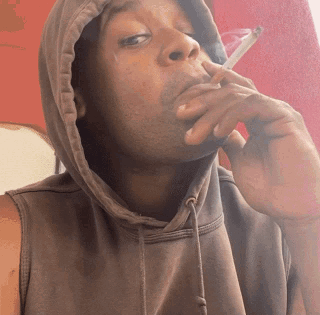 a man wearing a hooded sweatshirt is smoking a cigarette