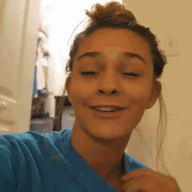 a woman in a blue shirt is smiling and looking at the camera