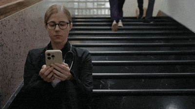 a woman is sitting on a set of stairs looking at her cell phone