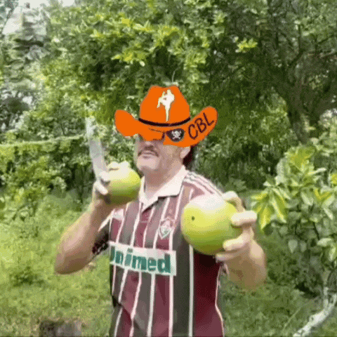 a man wearing a cowboy hat and a unimed shirt is holding two apples