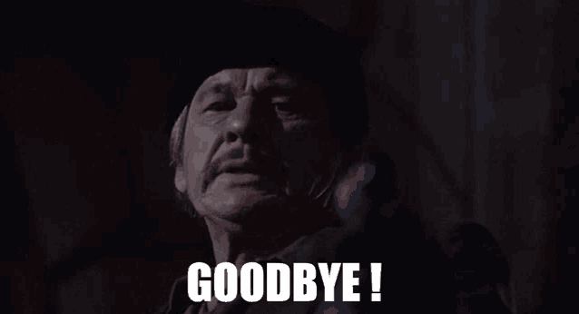 a man in a cowboy hat is saying goodbye in a dark room .