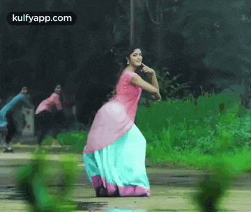 a woman in a pink dress and blue skirt is dancing in the rain .