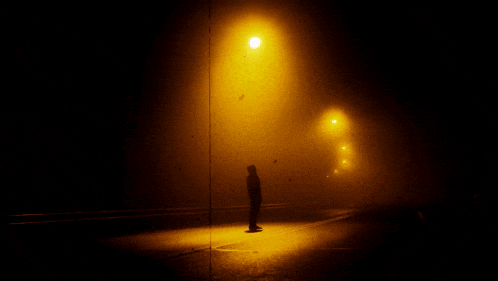 a silhouette of a person standing under a street light