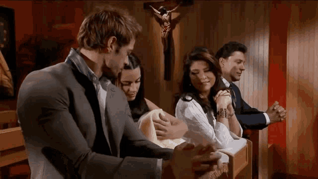 a group of people praying in a church with a jesus cross in the background