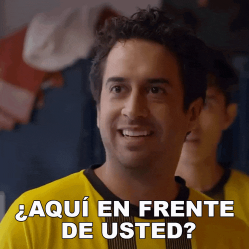 a man in a yellow shirt is smiling and asking " aqui en frente de usted "