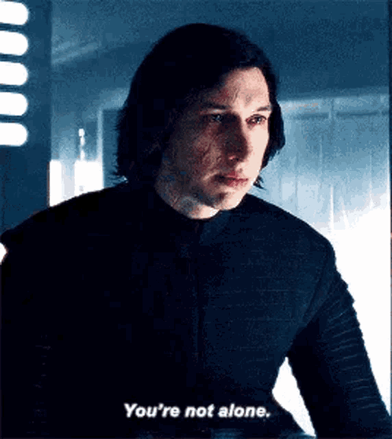 a man in a black shirt is talking to another man in a room .