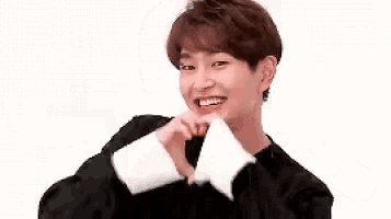 a young man in a black sweater is making a funny face and smiling .