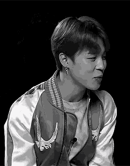 a black and white photo of a young man wearing a jacket with wings on it .