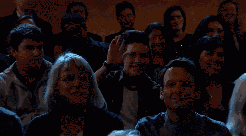 a group of people are sitting in a dark room and one of them is wearing a shirt that says ' a ' on it