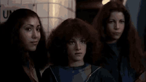 three women with long red hair are standing next to each other .
