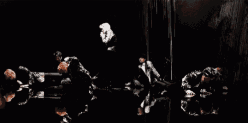 a group of people are dancing in a dark room with their reflections in the water .