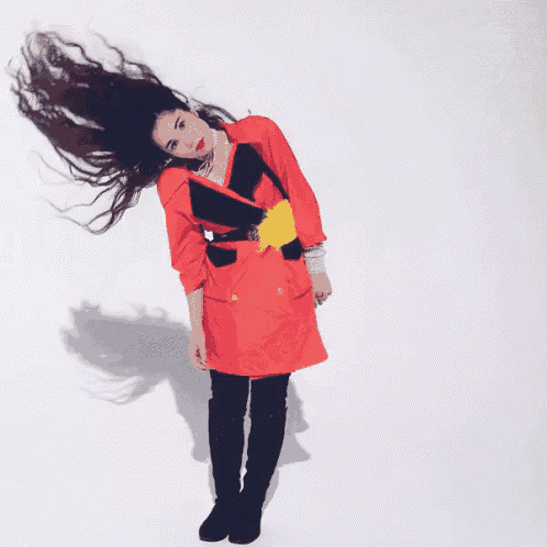 a woman wearing a red jacket and black pants is laying on her back