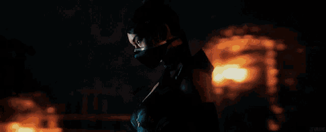 a woman wearing a mask is standing in front of a burning building