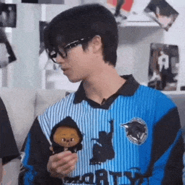 a man wearing glasses is holding a stuffed animal in his hand .